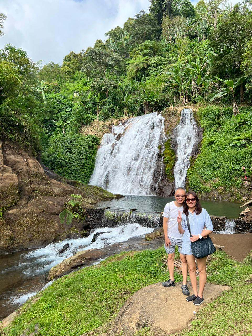 Couple beside a waterfall and river in green hills