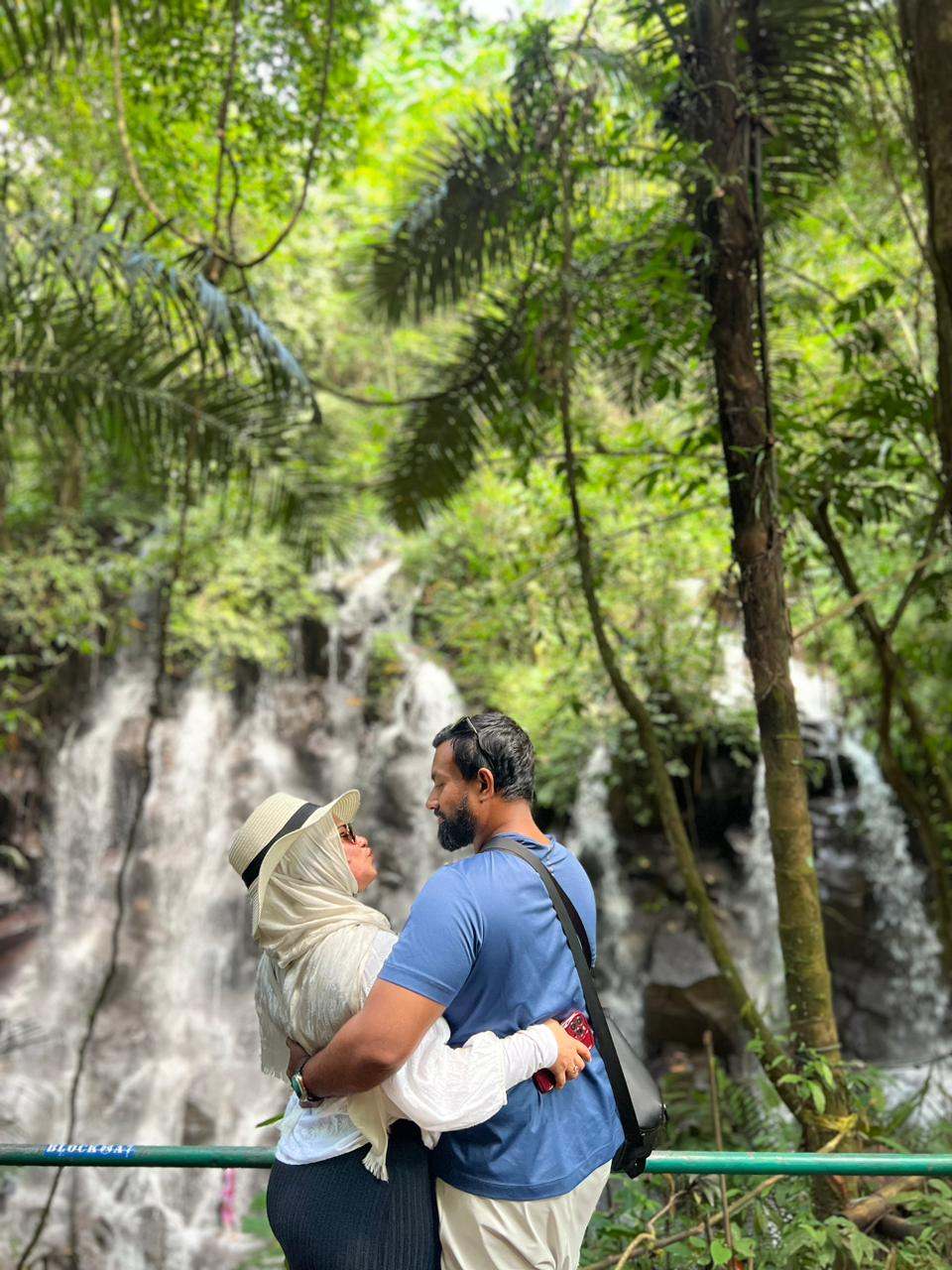 Couple embracing in front of a jungle waterfall