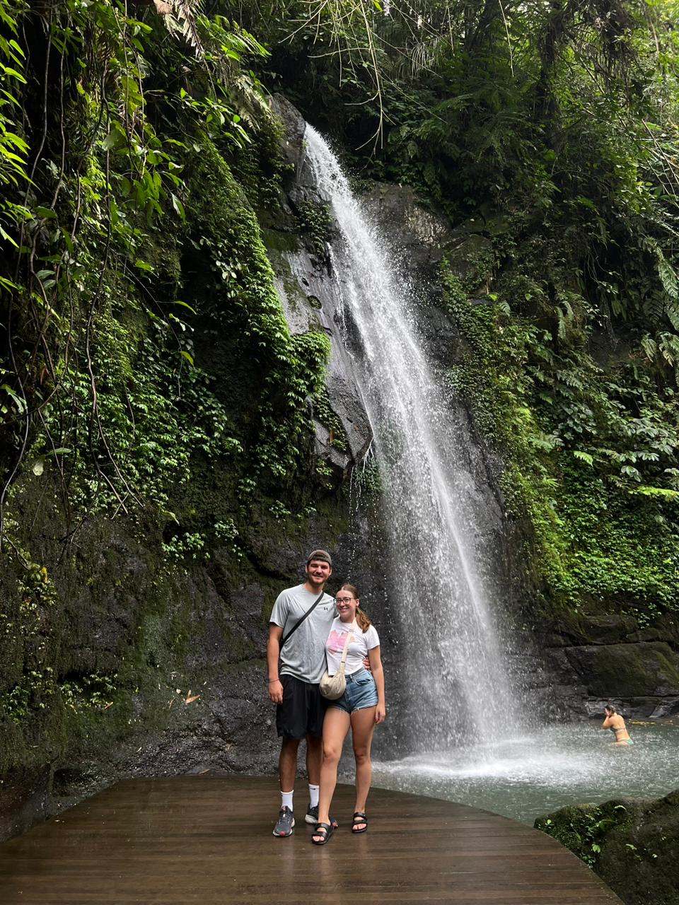Couple in front of a waterfall pouring into a pool