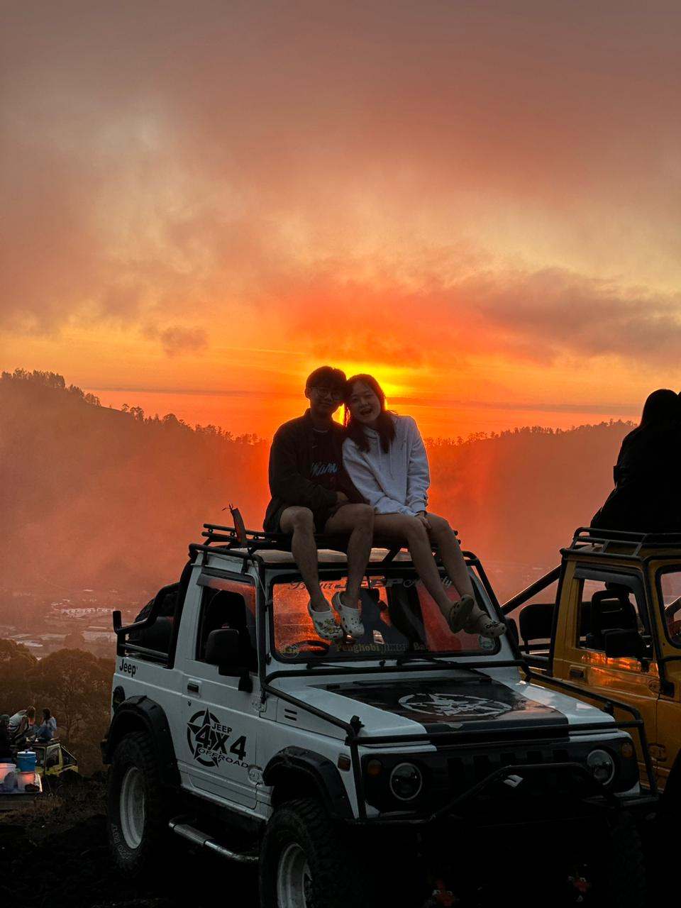 Couple on a jeep roof watching the sunrise, Mount Batur