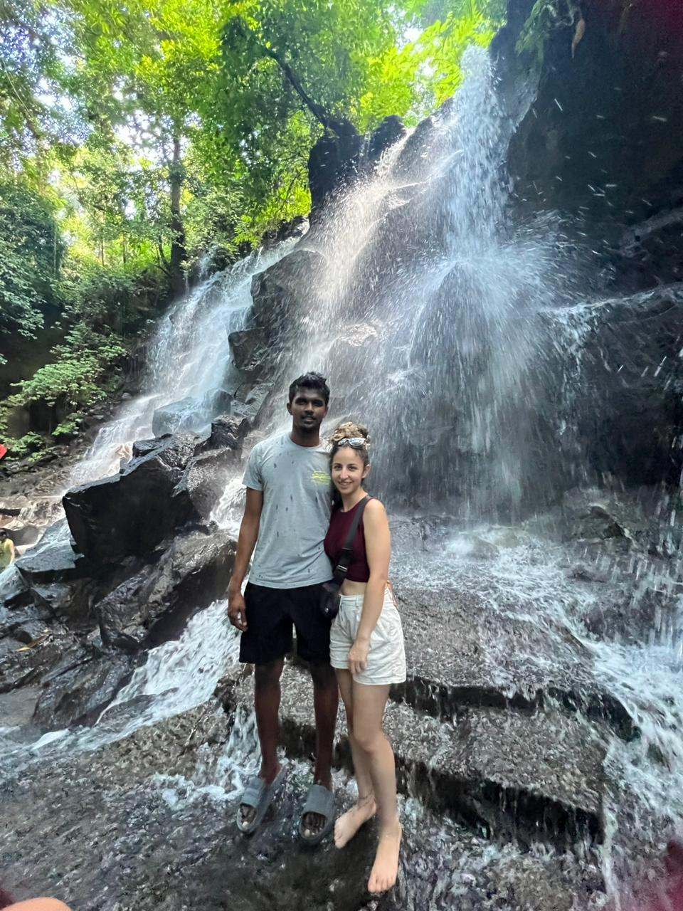 Couple standing on rocks beside a rushing waterfall