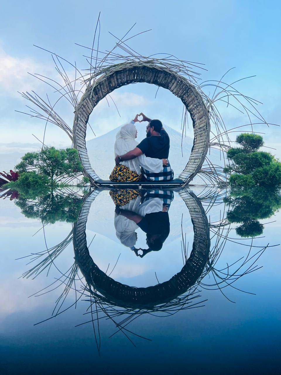 Couple in a woven ring frame reflected in water