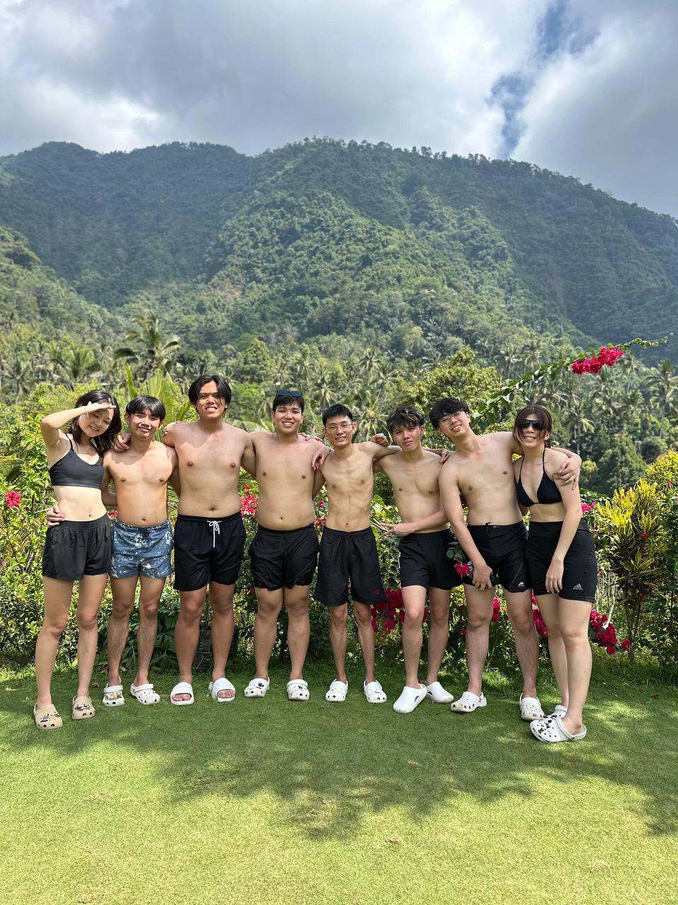 Group of guests in swimwear in front of green mountains