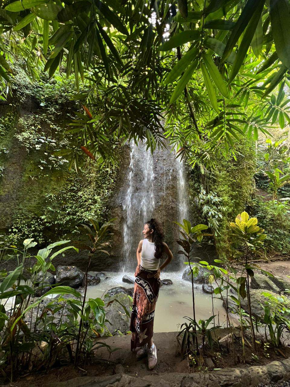 Guest in front of a small jungle waterfall
