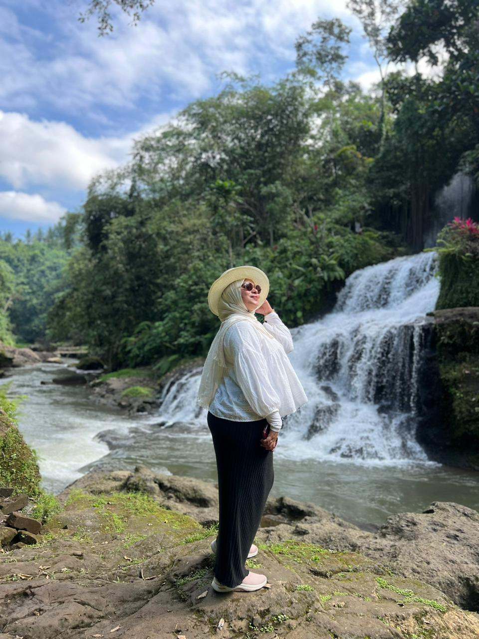 Guest in a hat beside a waterfall