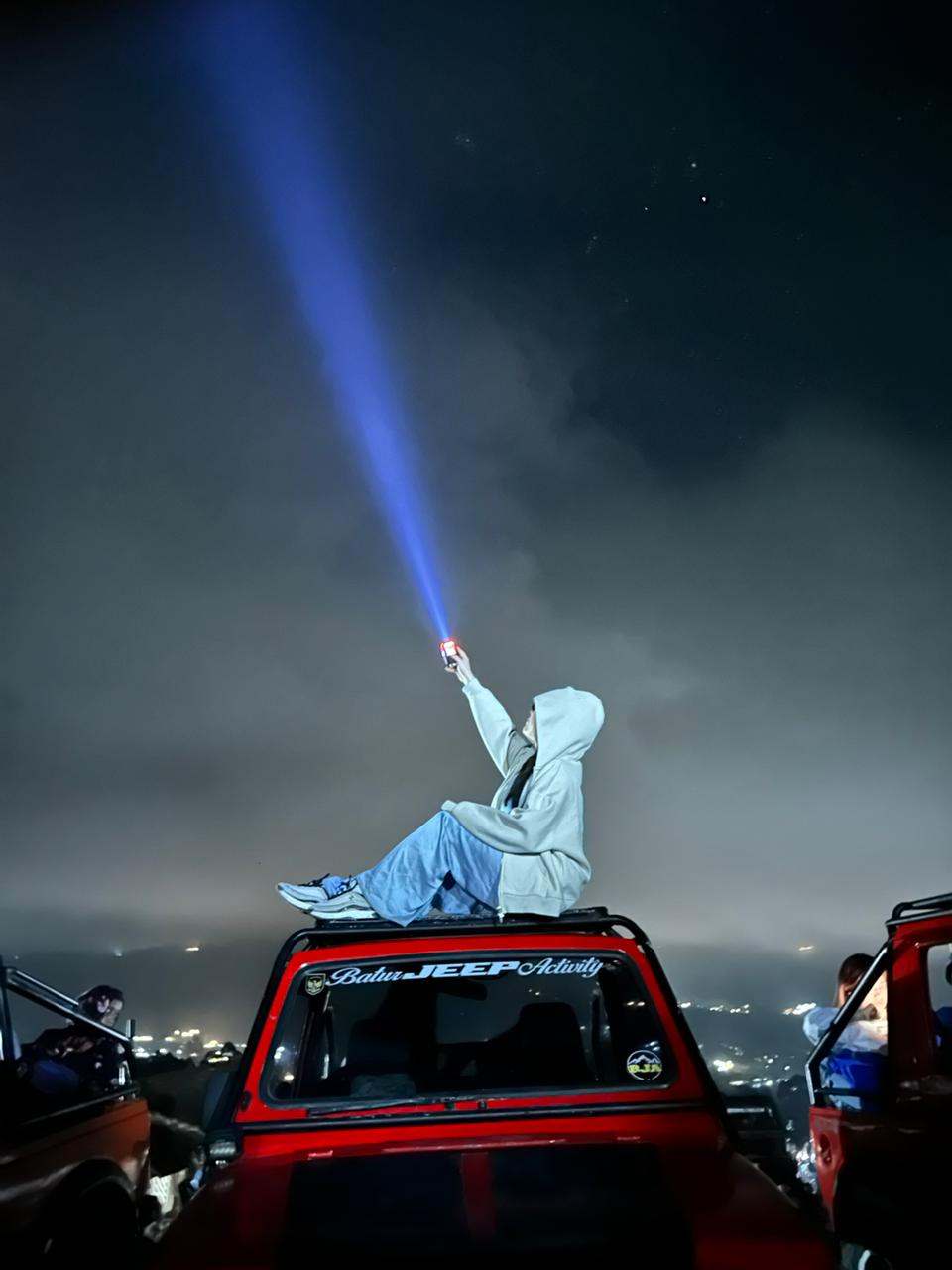 Guest holding a flashlight beam into the night sky, Mount Batur