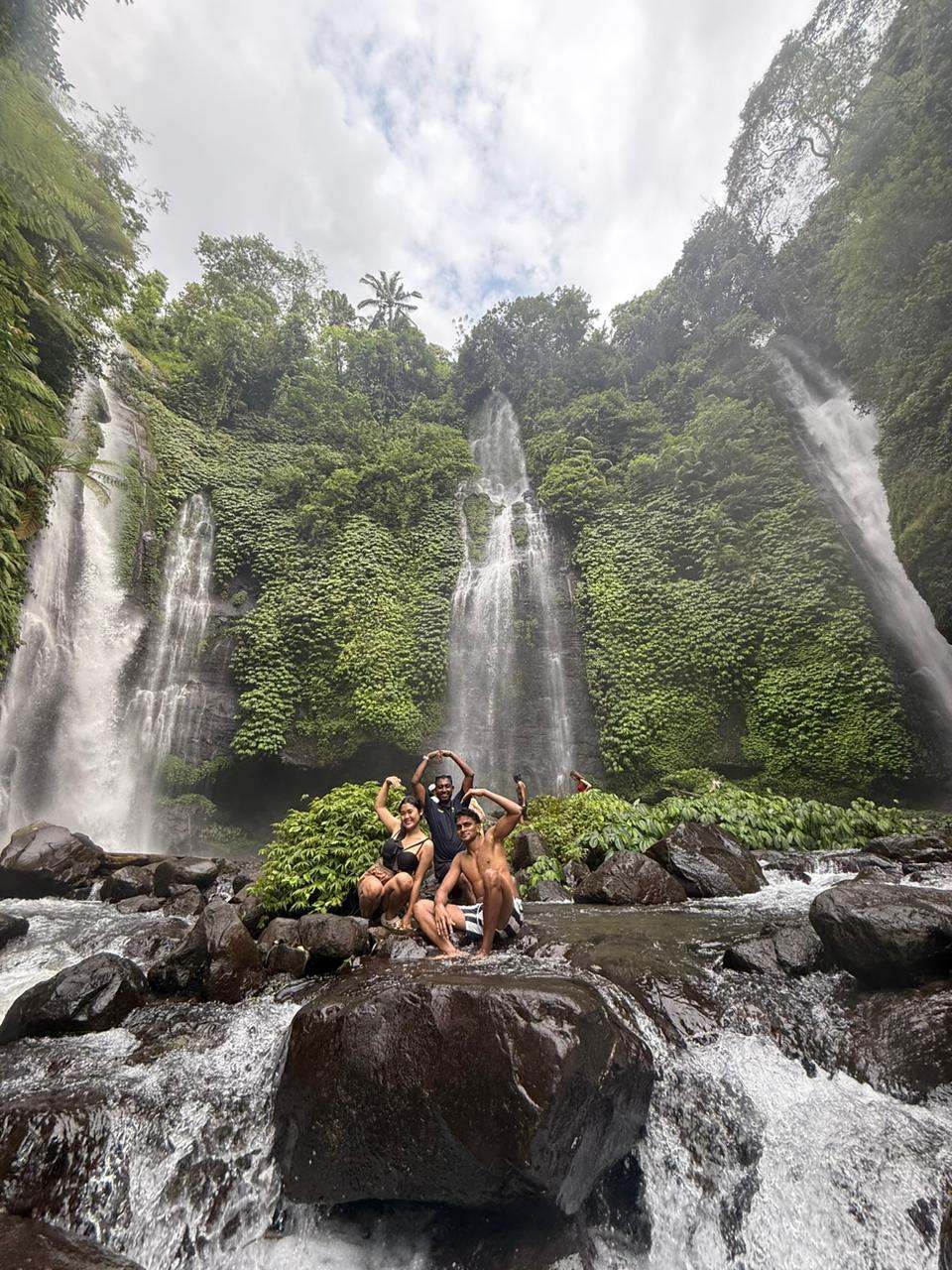 Guest posing on a boulder in front of twin waterfalls