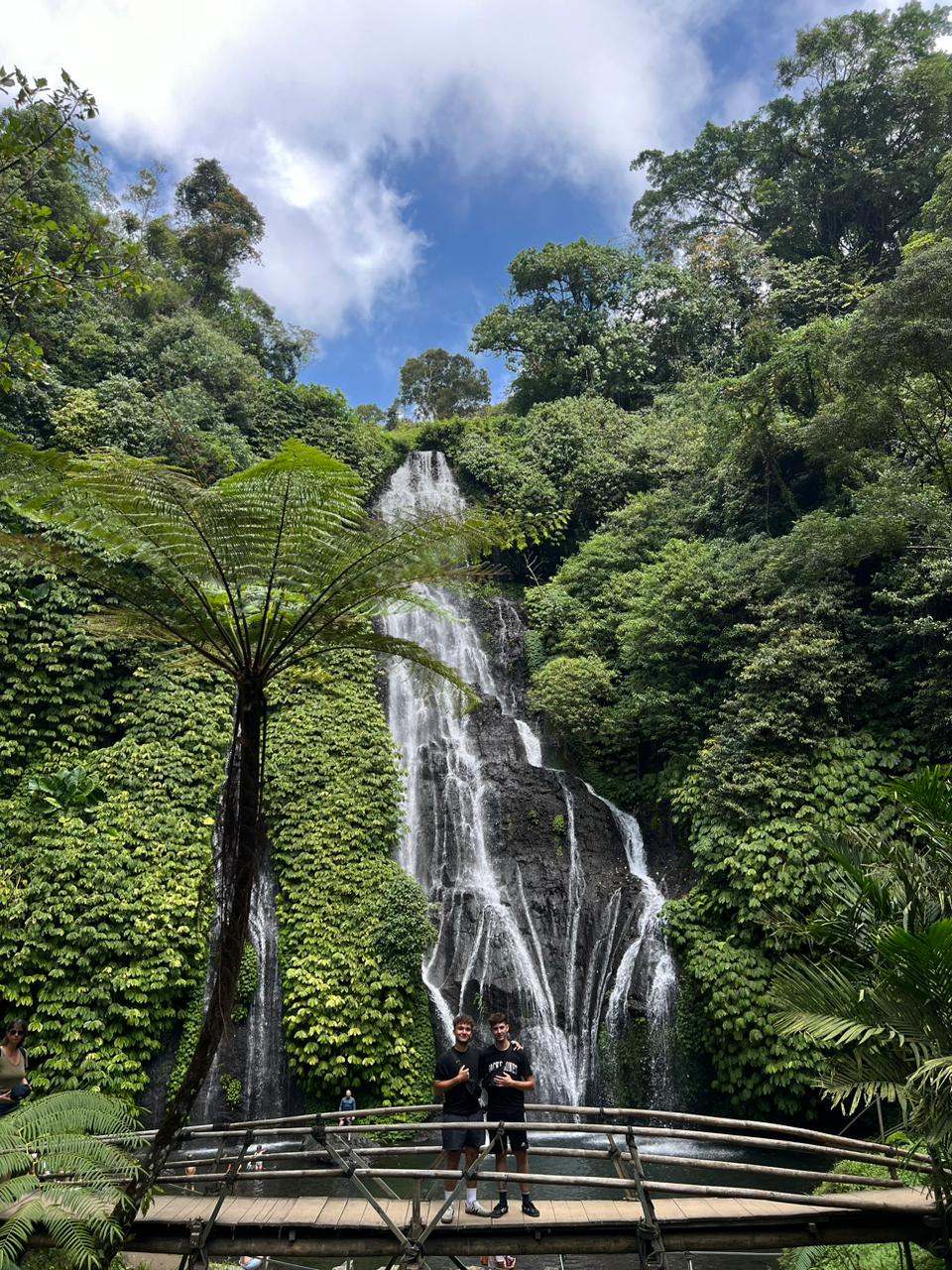 Guests on a bridge in front of a tall waterfall