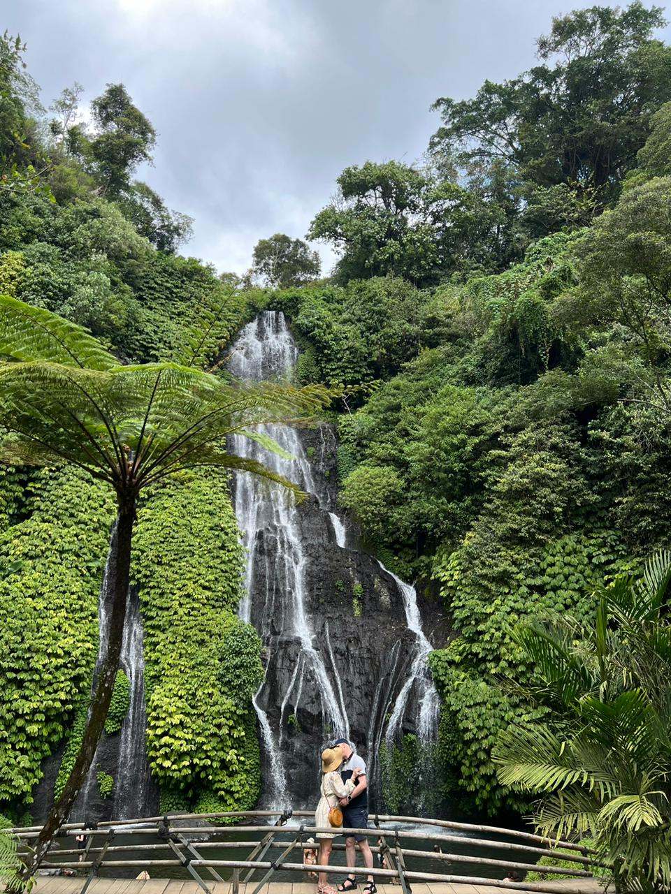 Guests at the foot of a tall jungle waterfall in Bali