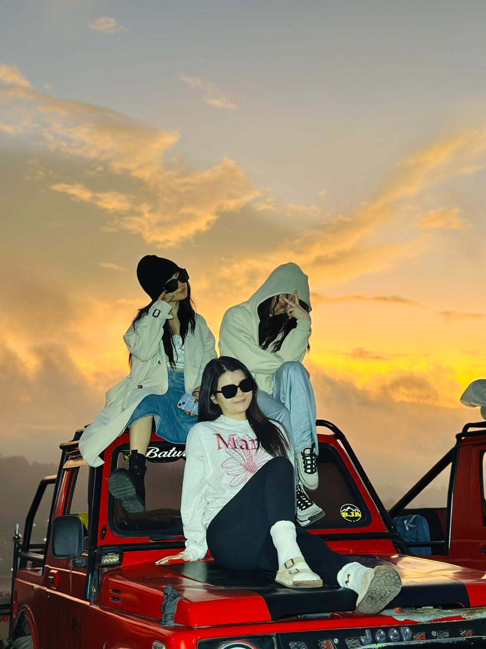 Three friends on a jeep roof at sunrise, Mount Batur