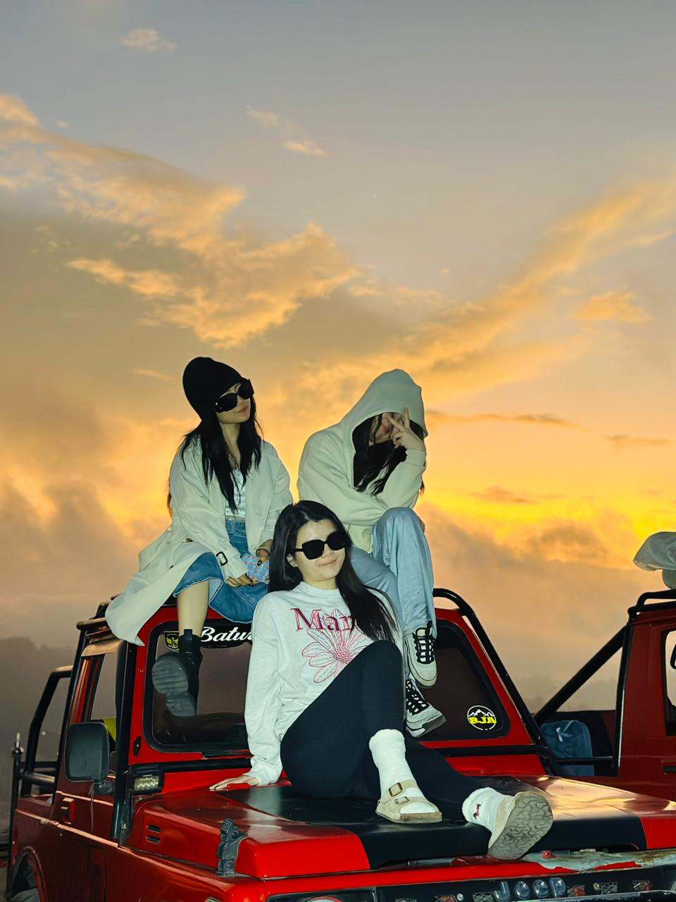 Three guests on a red jeep at golden sunrise