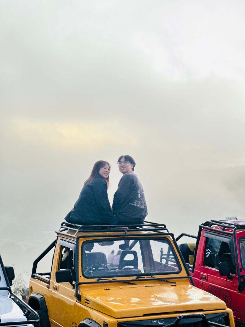 Two guests on a jeep roof in the morning mist, Mount Batur