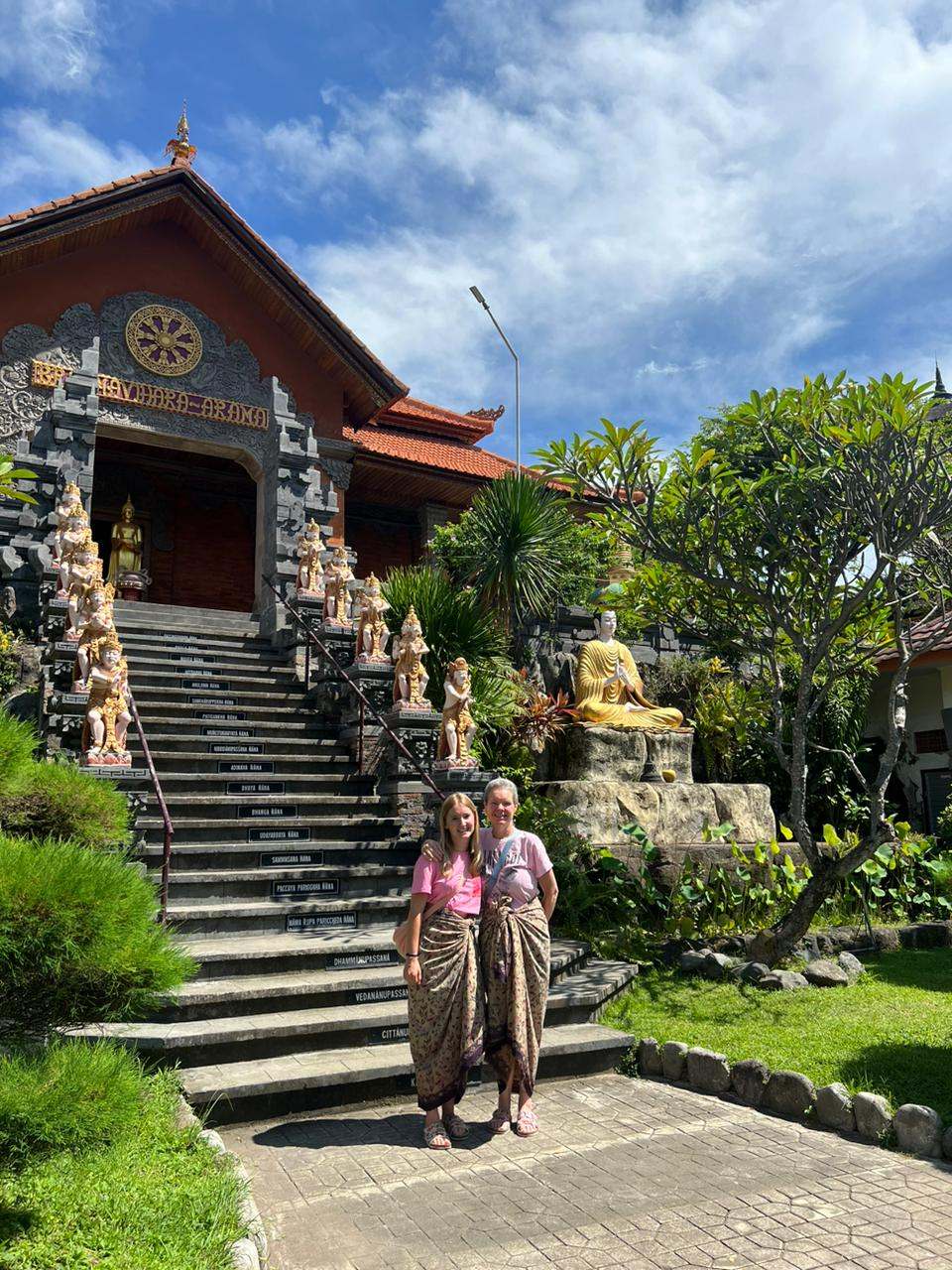 Two guests in sarongs on temple stairs