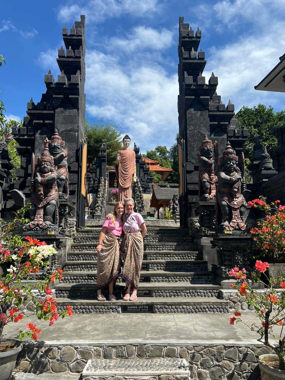 Two guests on the steps of a split temple gate with flowers