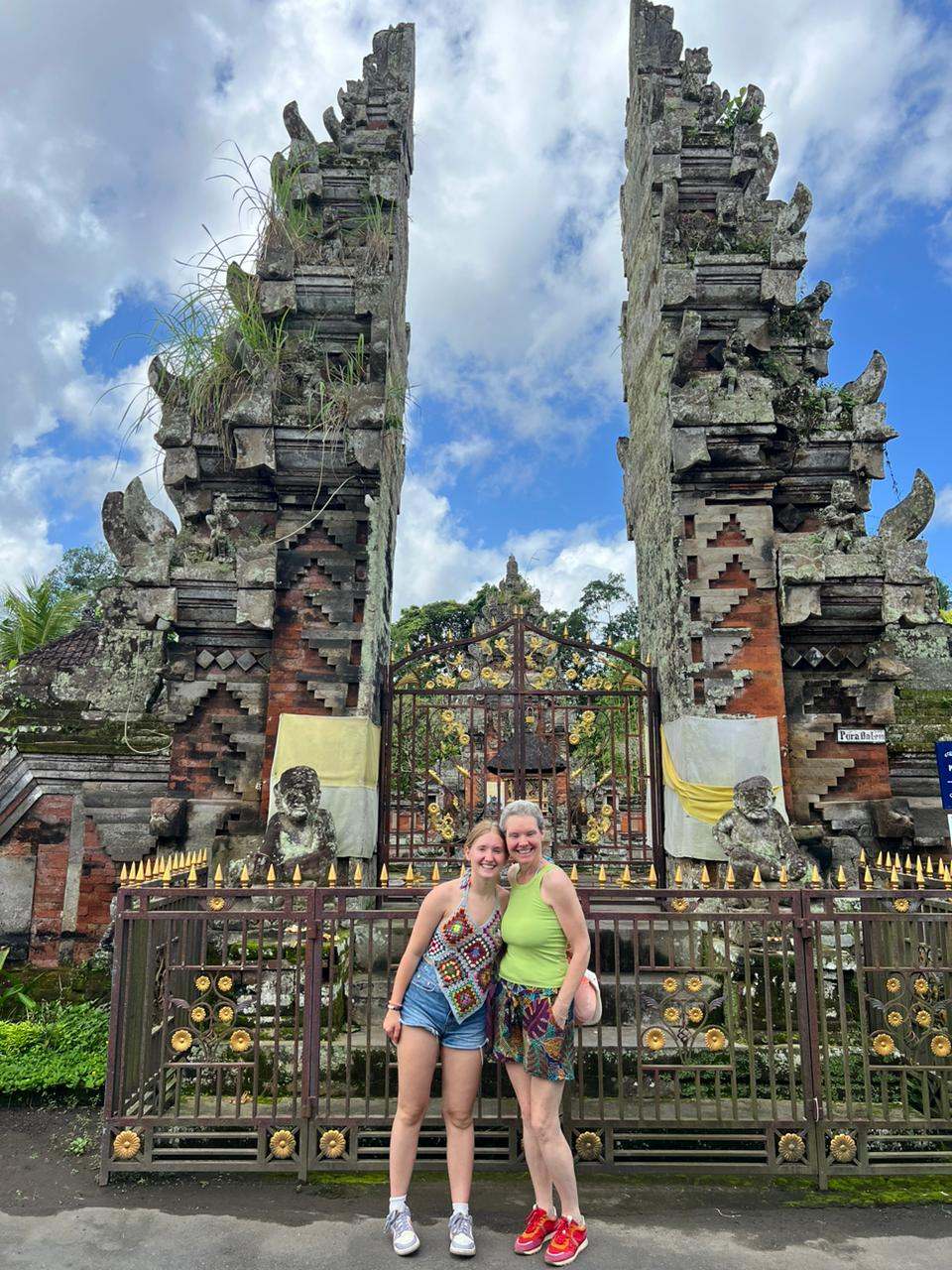 Two guests at a tall split gate temple under blue sky